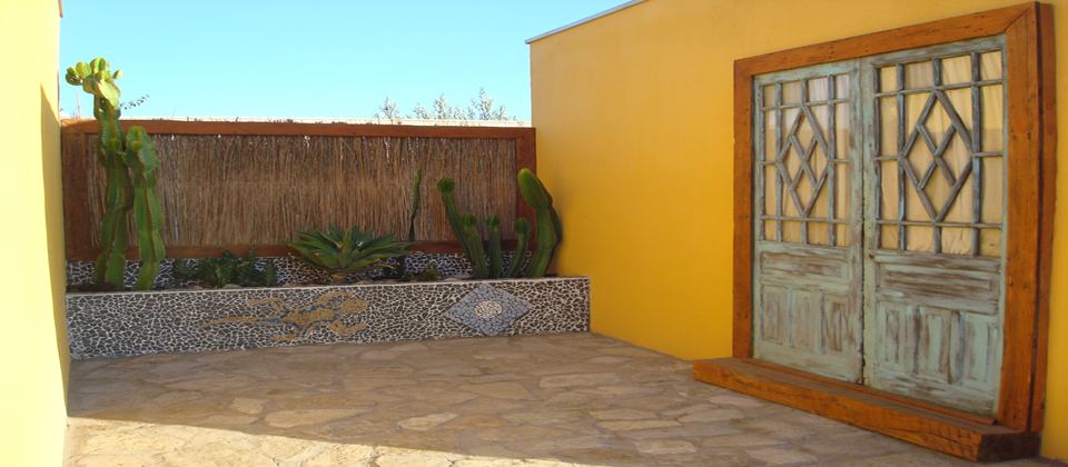 Patio interior de Atacama Lodge con cactus y puerta de madera artesanal en tono verde