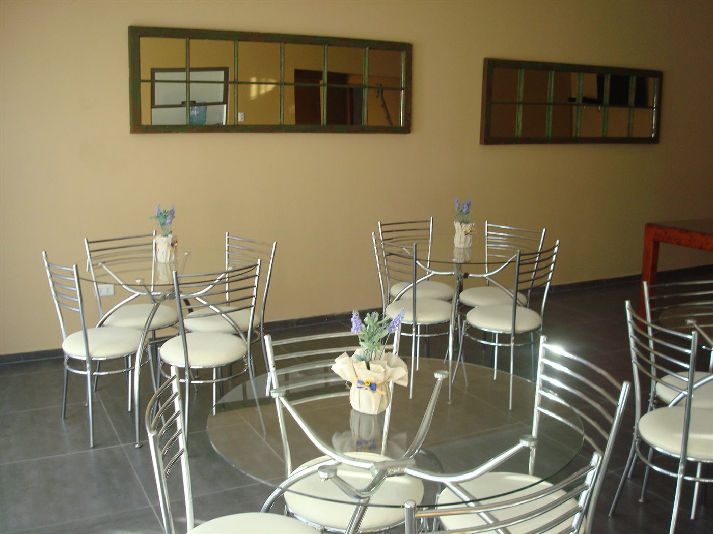 Sala con mesas redondas de vidrio para desayuno en Atacama Lodge
