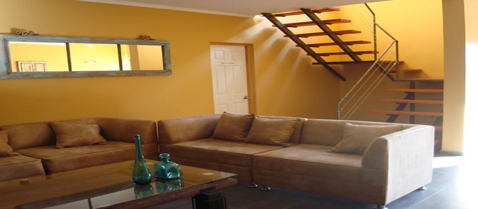 Living de Atacama Lodge con sillones y escalera de madera al segundo piso