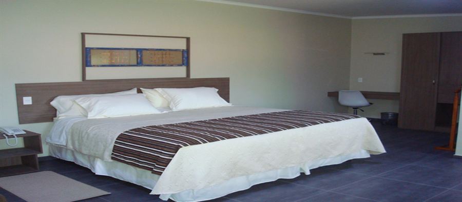 Suite de Atacama Lodge con cama amplia, cortinas y veladores a ambos lados