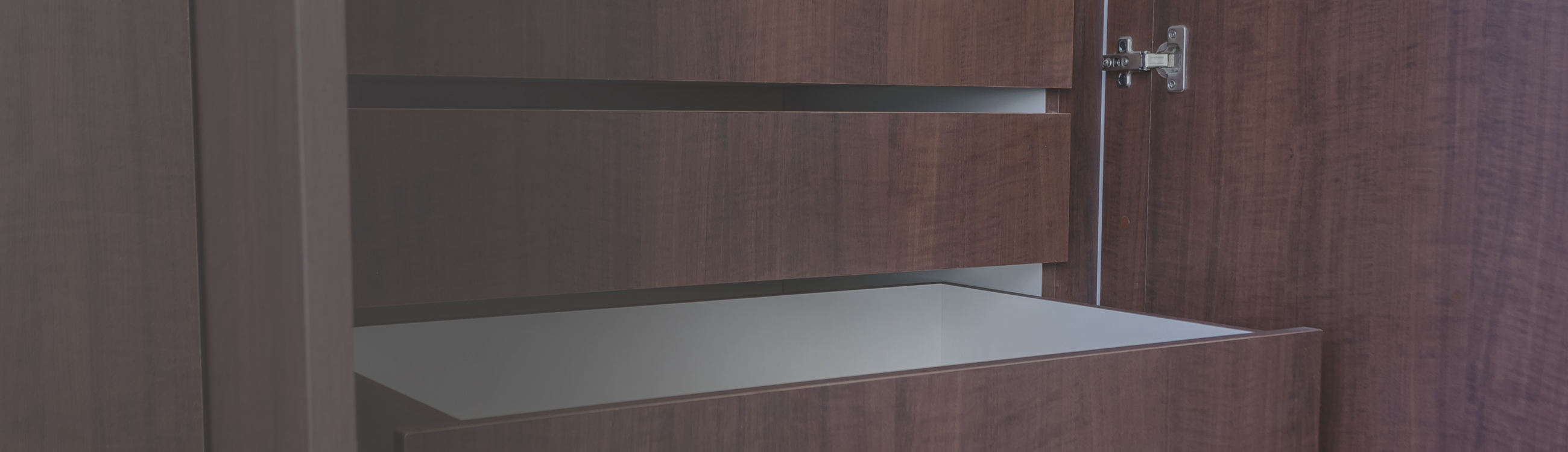 Interior de closet a medida en madera oscura con cajonera abierta, fabricado por Chilemuebles