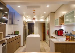 Cocina y living con muebles en melamina y una isla central iluminada, fabricados por Chilemuebles