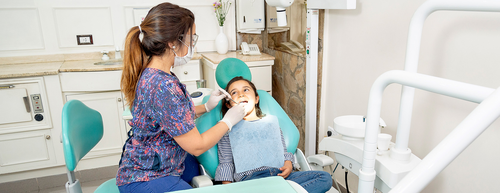 Odontóloga de Clínica COP atendiendo a una niña en el sillón odontológico