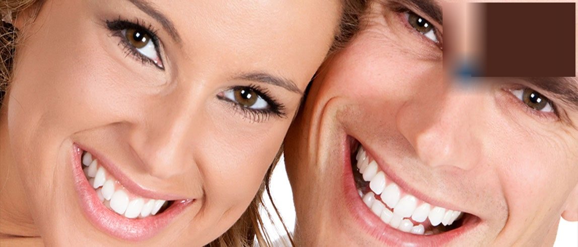 Pareja de pacientes sonriendo tras su tratamiento de estética dental