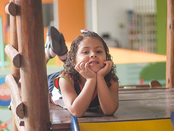 Criança sorrindo em brinquedo de escorregar no parque do Colégio Conexão Saber
