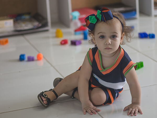 Criança pequena da Educação Infantil brincando no chão da sala