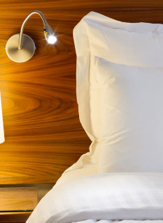 Habitación Estándar del Eurohotel Panamá con lámpara de lectura y ropa de cama blanca