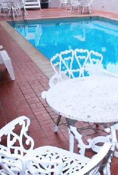 Piscina del Eurohotel Panamá con mobiliario blanco y deck de piso rojo