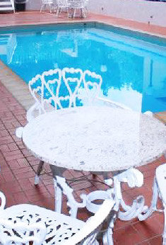 Detalle de la piscina del Eurohotel Panamá con sillas y mesa de hierro forjado