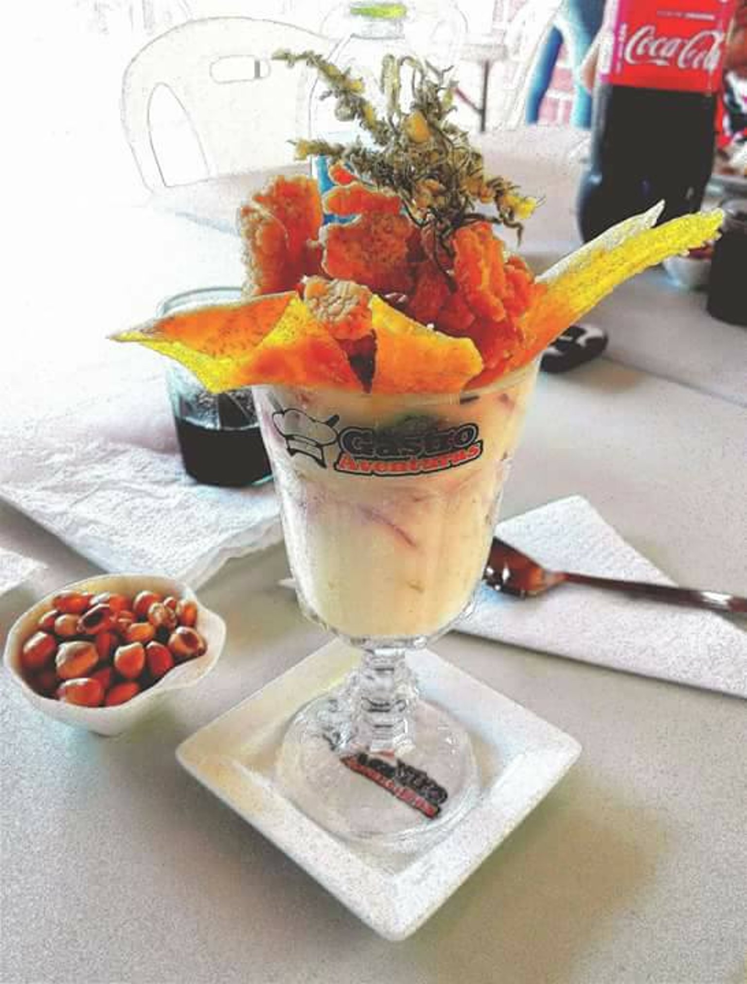 Postre helado servido en copa con la marca GastroAventuras, crocante y hierbas de la selva