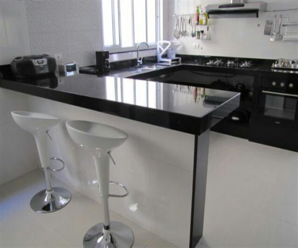 Cozinha em granito preto polido com balcão e cooktop, obra GranMármores