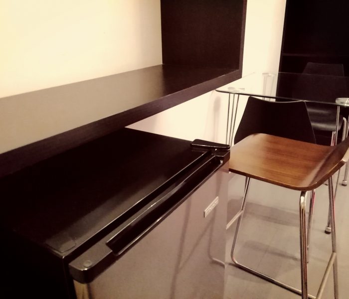 Comedor del departamento tipo casa del Hostal Elixer, con mesa, sillas y escalera al fondo