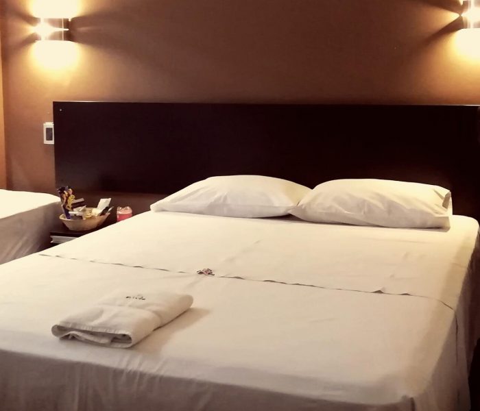 Habitación Doble del Hostal Elixer con dos camas, cabecera oscura y luces cálidas a los costados