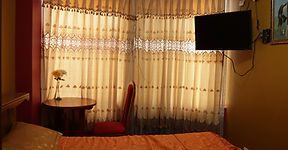 Habitación matrimonial del Hostal Flor Andina con cama, TV y cortinas