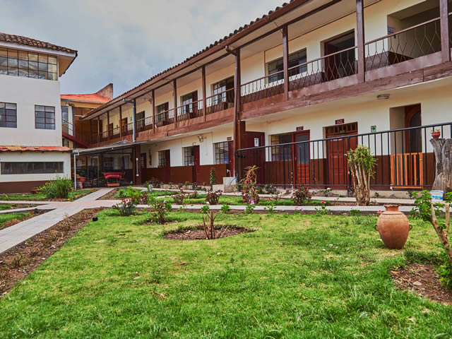 Fachada y jardín interior del Hostal Santa Rosa de Lima en Cusco, con balcones de madera y macetas de flores