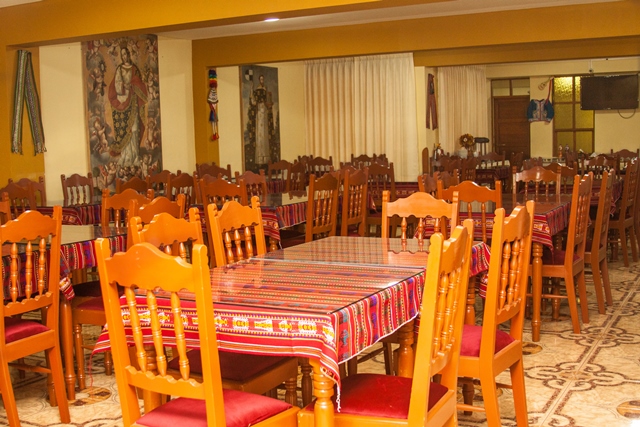 Comedor del hostal con cuadro colonial y mesas listas para el desayuno