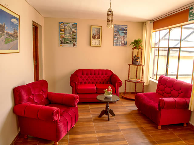 Sala de estar del Hostal Santa Rosa de Lima con sofás de terciopelo rojo