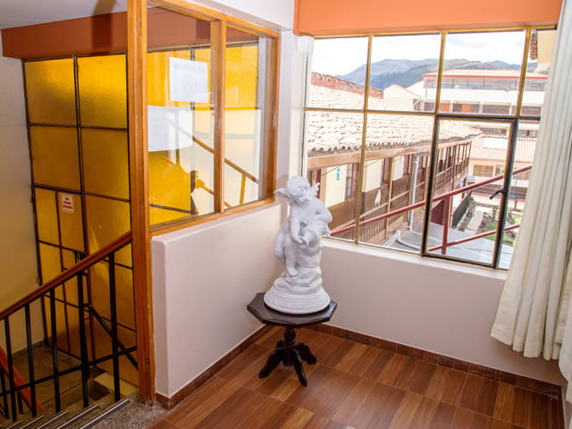 Escalera interior del hostal con vista a los techos de teja de Cusco