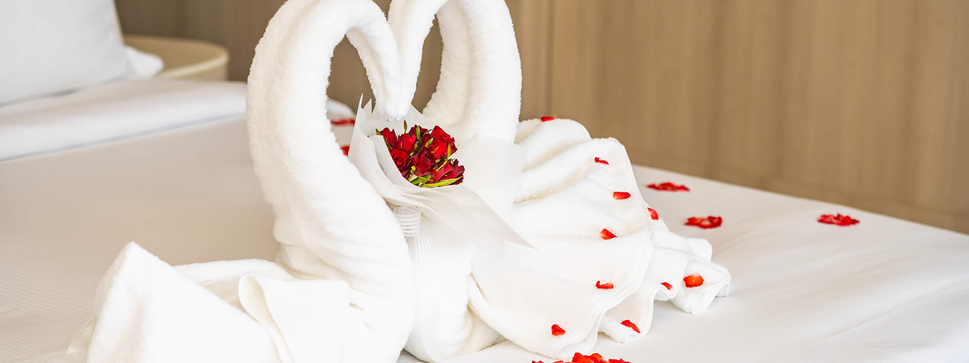 Detalle de toallas decorativas y rosas sobre una cama del hostal
