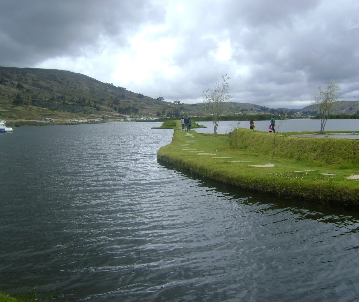 Laguna andina cerca de Riobamba con senderos, áreas verdes y montañas al fondo