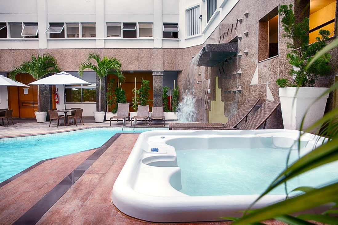 Piscina do Hotel Beira Mar com hidromassagem, deck e área de descanso durante o dia