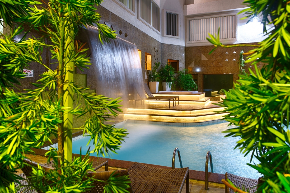 Cascata da piscina cercada por vegetação tropical no Hotel Beira Mar