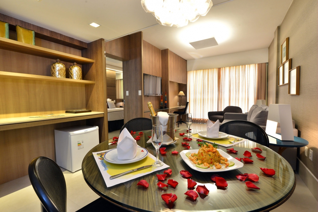 Suíte do Hotel Beira Mar com sala de estar e mesa de refeições
