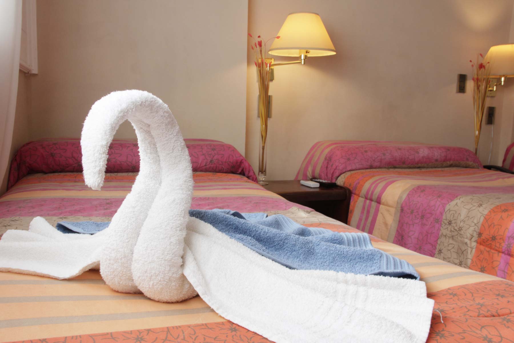 Habitación Doble Ejecutiva del Hotel Bertaina con cobertor de color y toalla decorativa en forma de cisne