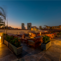 Terraza con sofás y fogata al atardecer, con el skyline de Cartagena de fondo