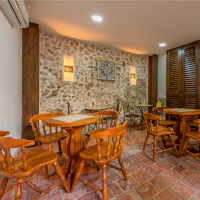 Zona de comedor del hotel con muros en piedra y mesas de madera rústica