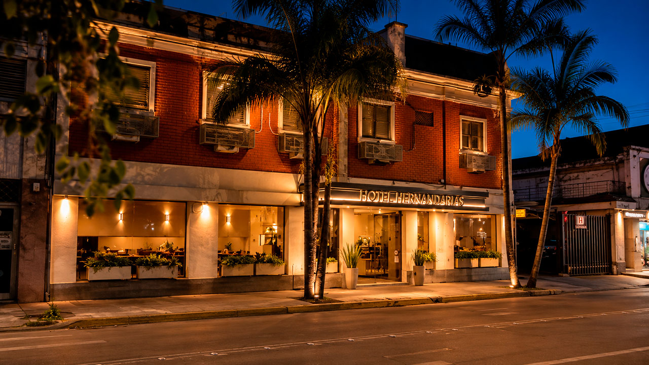 Fachada del Hotel Hernandarias al atardecer, con palmeras y cielo azul
