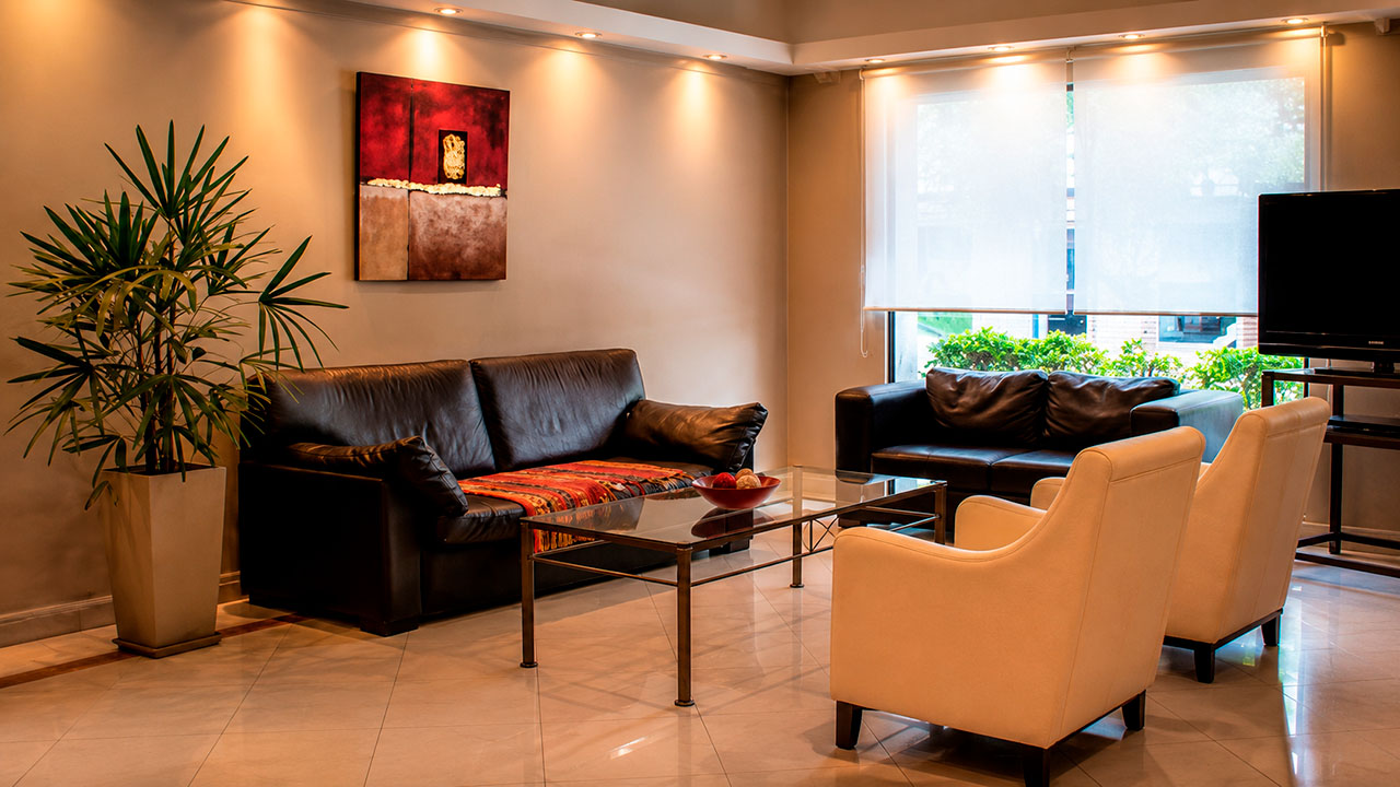 Living del Hotel Hernandarias con sofás de cuero y mesa ratona de vidrio