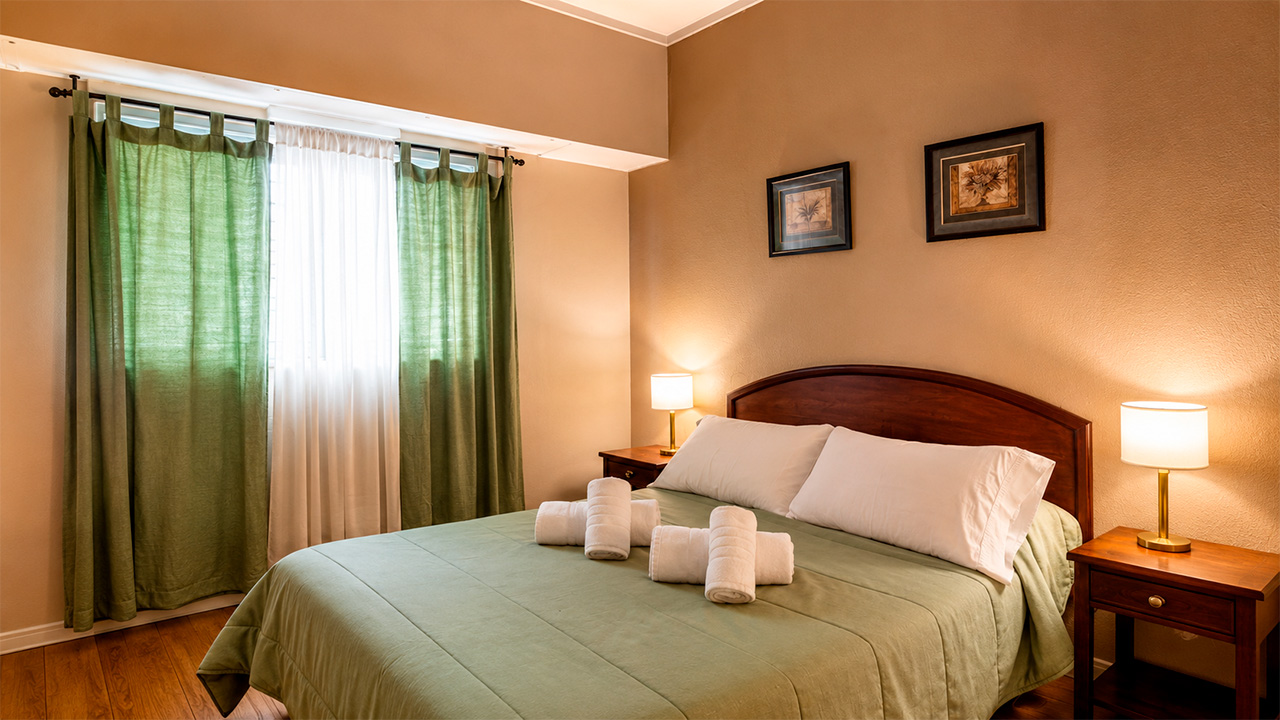 Habitación Matrimonial del Hotel Hernandarias con cama de dos plazas y cobertor verde