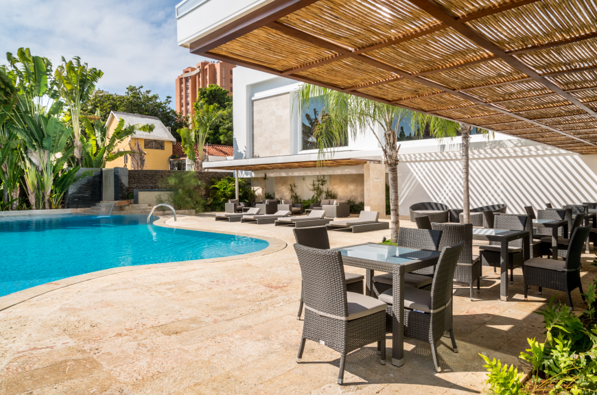 Terraza junto a la piscina del Hotel Kristoff con mobiliario y solárium