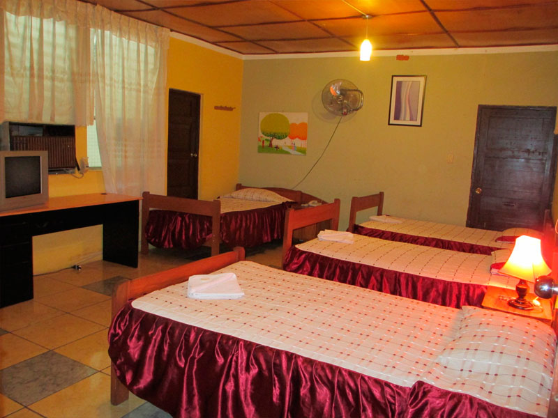 Habitación Cuádruple del Hotel Tarapoto Inn con cuatro camas, escritorio y televisor