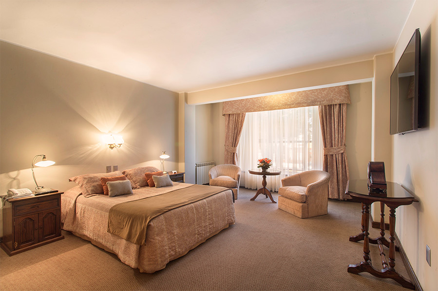 Habitación Matrimonial del Hotel Tierra del Fuego con cama doble, living y calefacción