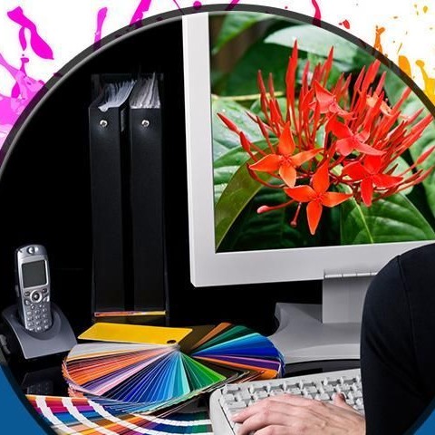 Escritorio de diseño con guías de color Pantone, computadora y teléfono, preparando un arte para su impresión