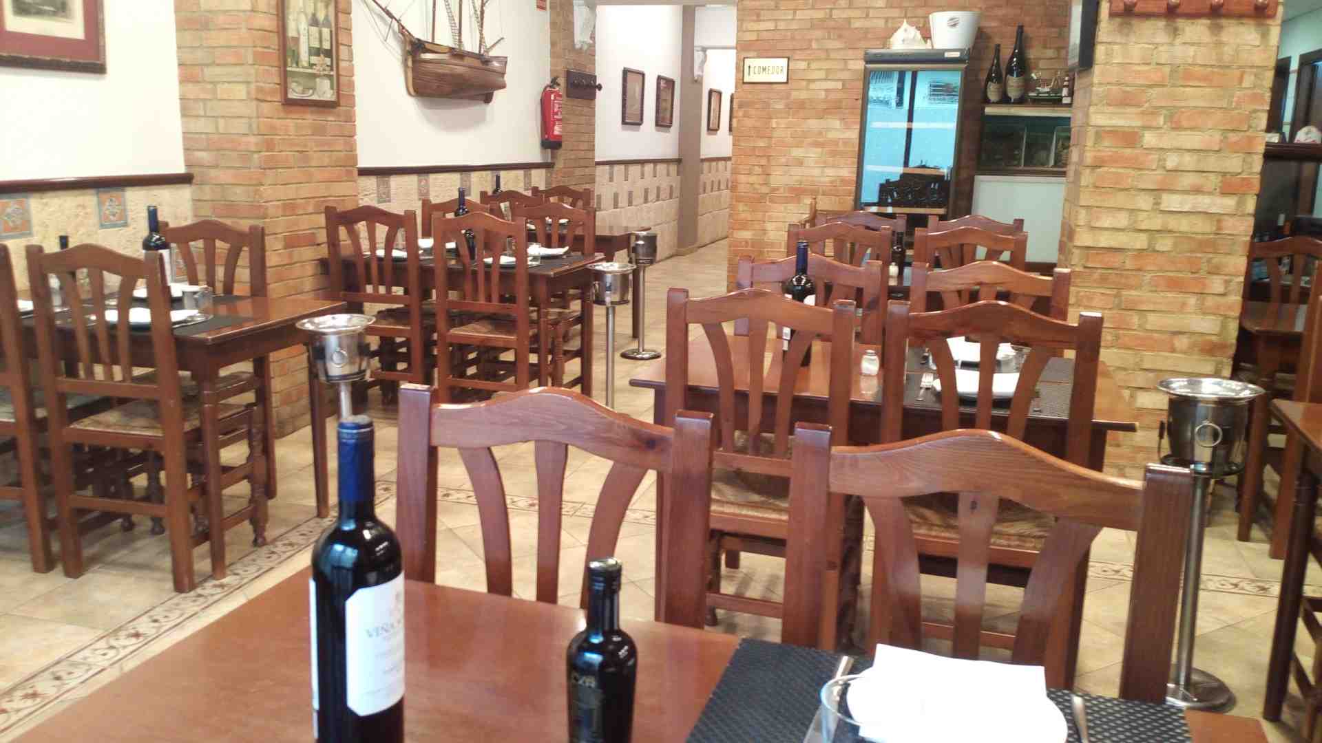 Comedor con paredes de ladrillo visto y mesas vestidas en el Restaurante Islas Canarias