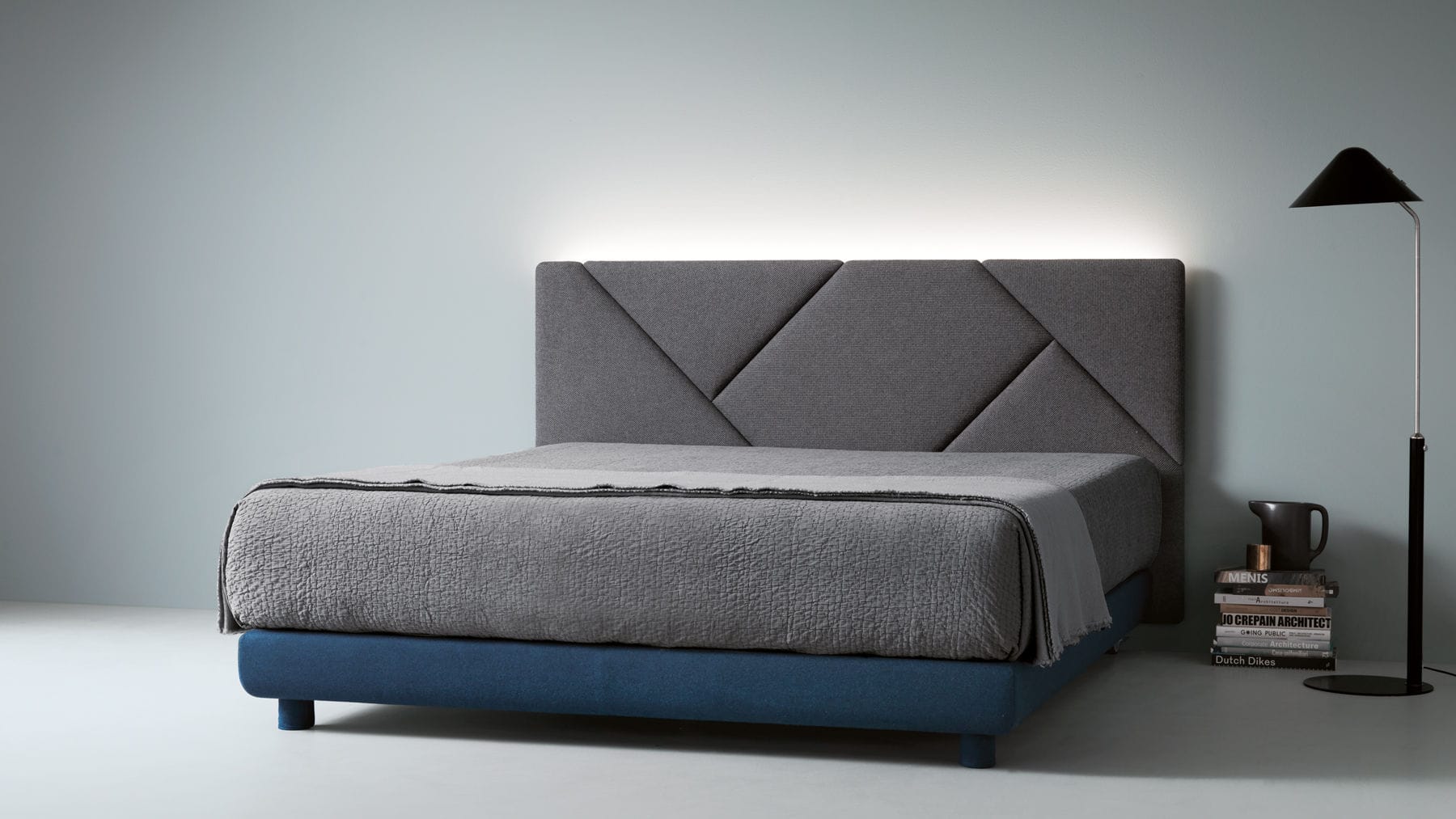 Cama tapizada con cabecero alto en tela gris, disponible en Muebles Casa sobre la Roca