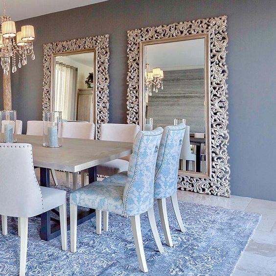 Comedor con espejos ornamentados y sillas en tela azul, disponible en Casa sobre la Roca