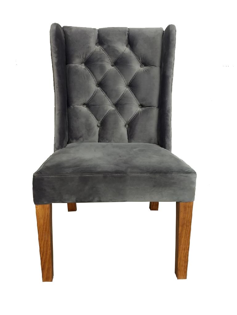 Sillón wingback tapizado en terciopelo gris con botonadura capitoné y patas de madera maciza