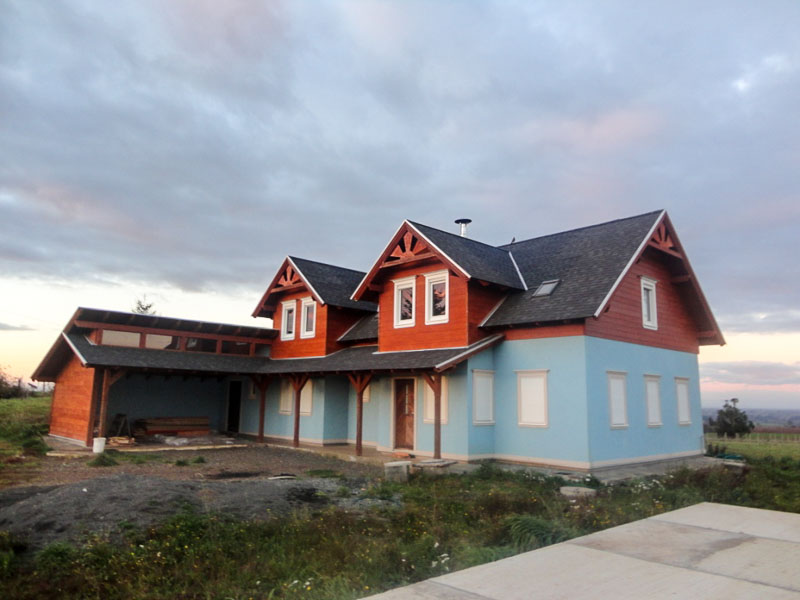 Casa en madera construida por Muebles HZ, con revestimiento exterior azul y estructura de techumbre en madera nativa
