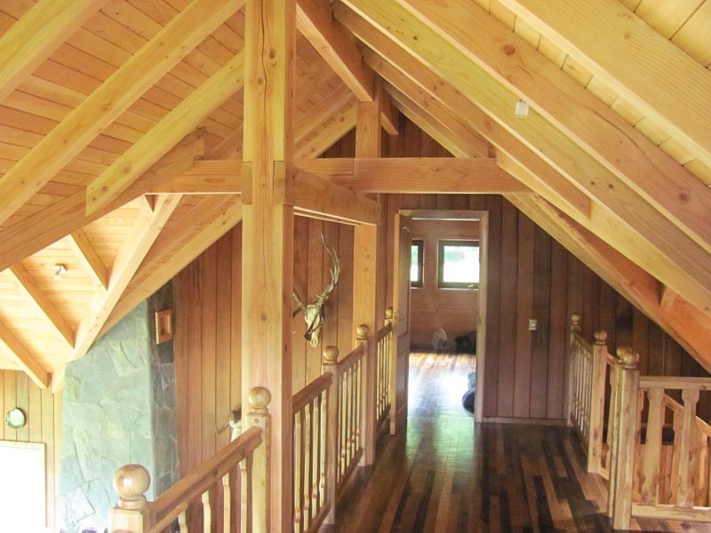 Pasillo interior con barandas de madera torneada en una casa construida por Muebles HZ