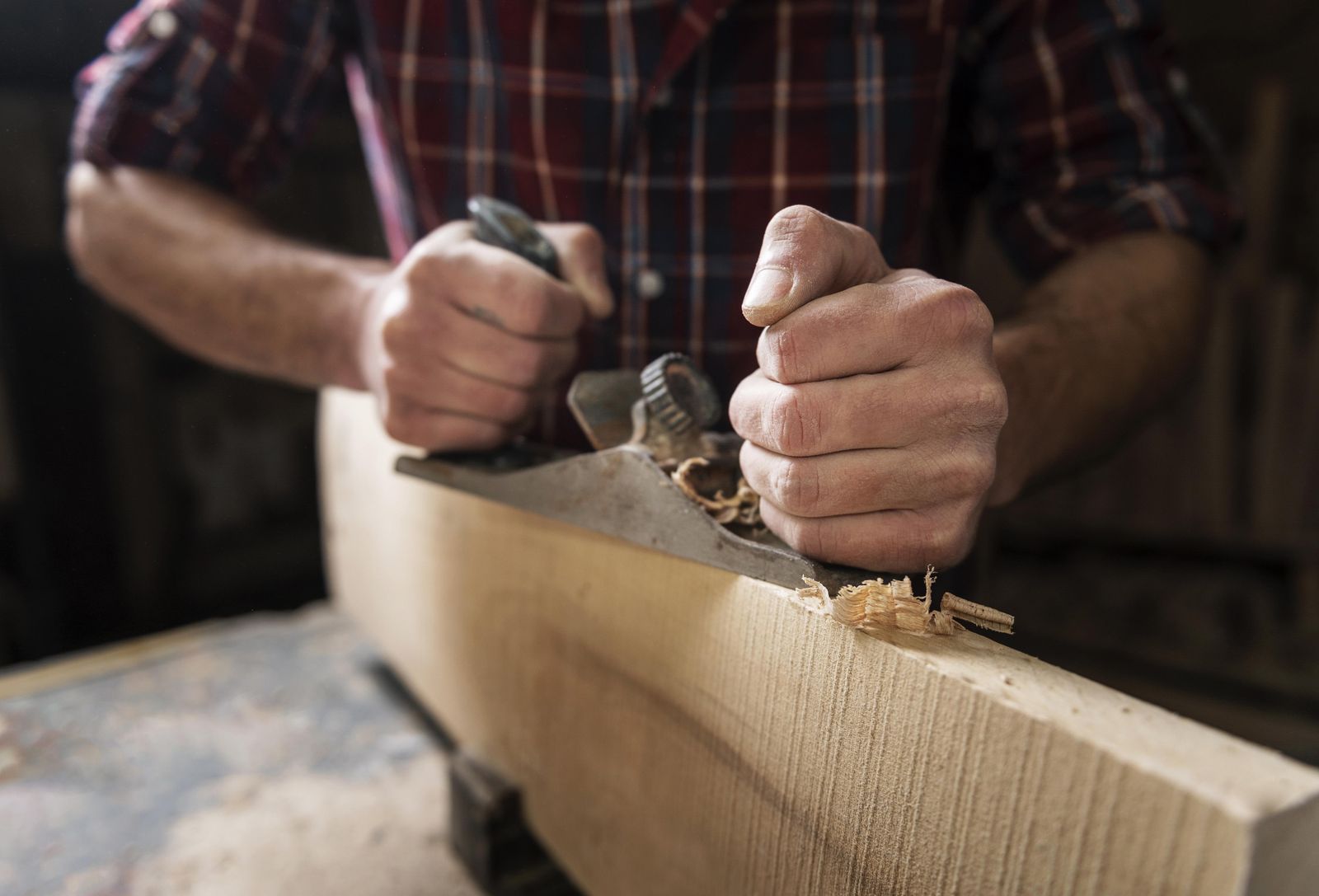 Carpintero cepillando a mano un listón de madera en el taller de Muebles Lasch