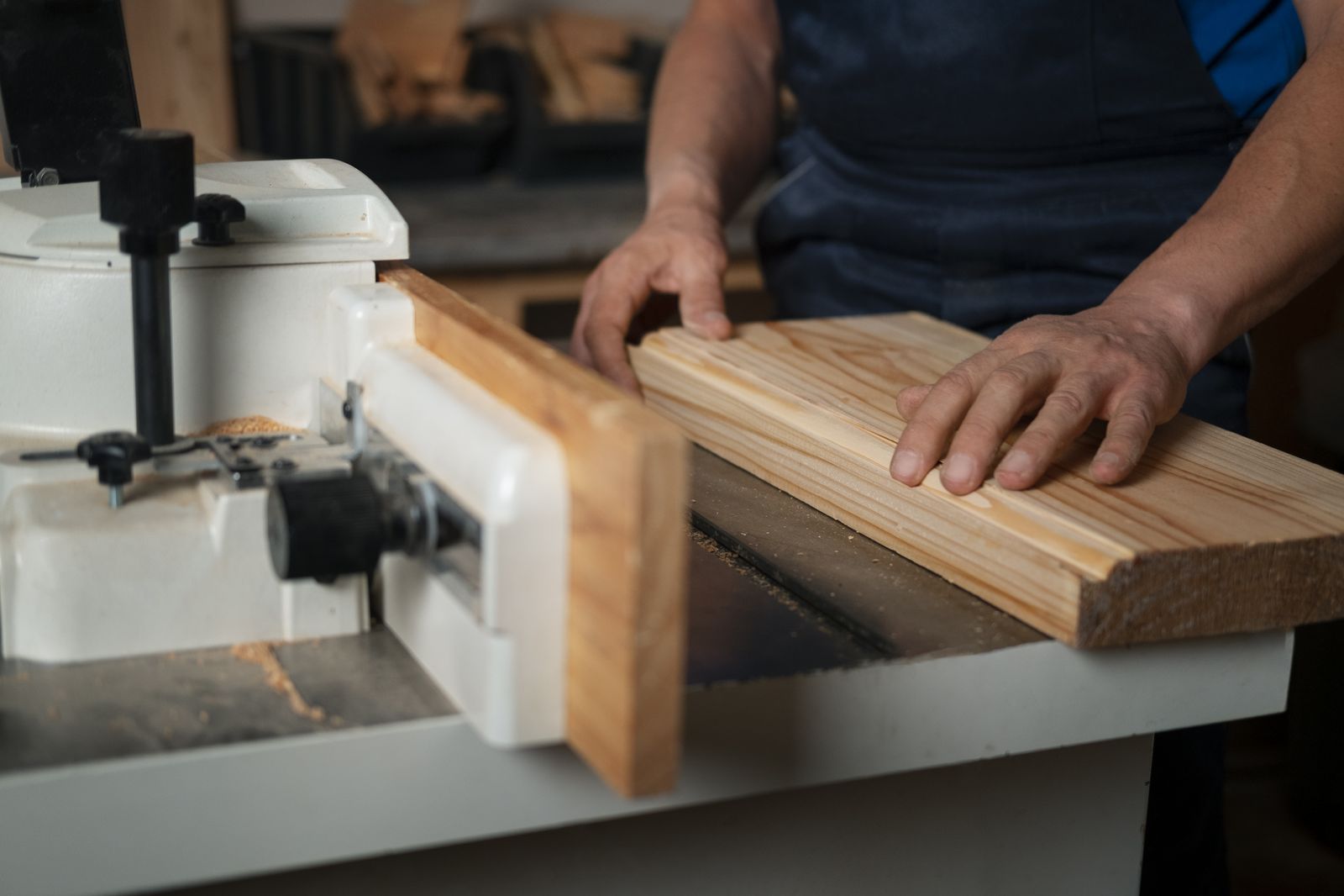 Carpintero ajustando una tabla de madera en una máquina cortadora de precisión