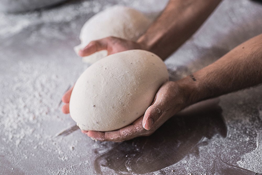 Manos dando forma a bolas de masa de pan sobre la mesa