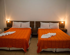 Habitación doble de la Posada Churum Merú con dos camas y ropa de cama color naranja