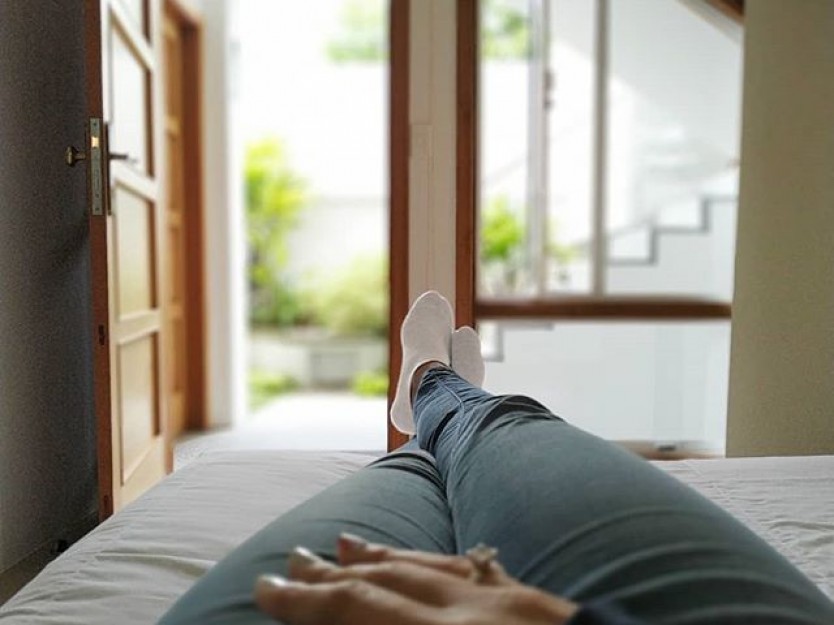Huésped descansando sobre la cama de una habitación de Posada Tramontana, con la puerta abierta hacia el jardín