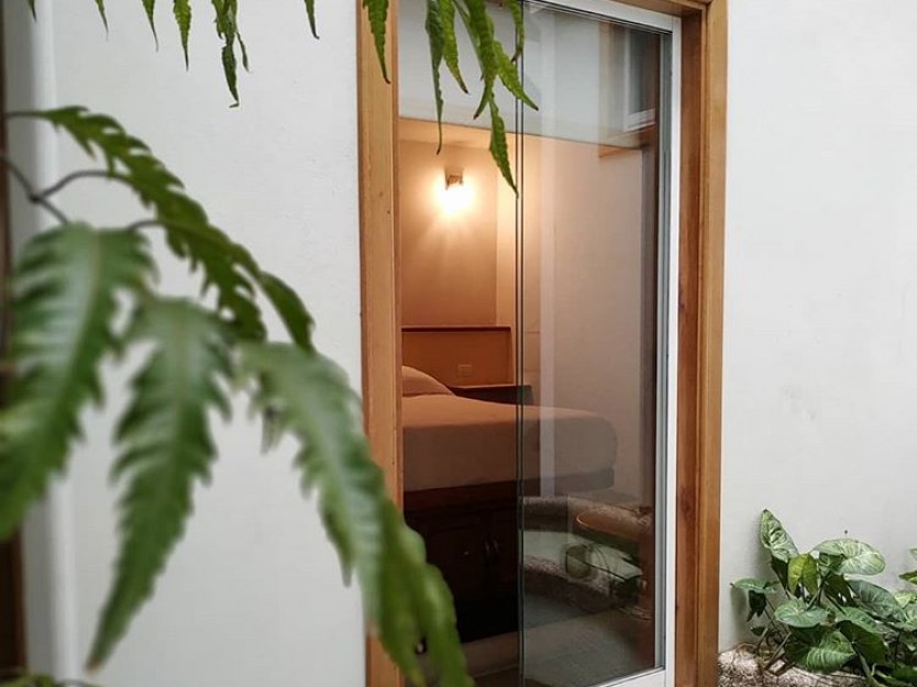Habitación Matrimonial de Posada Tramontana con vista al jardín interior desde la puerta de vidrio