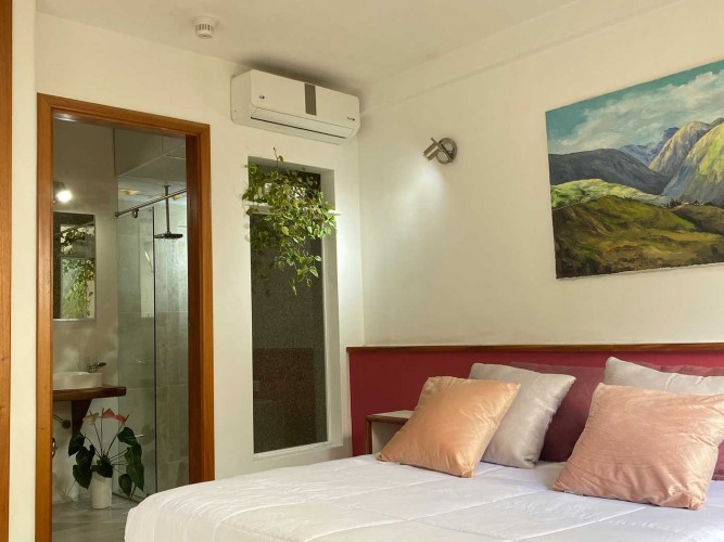 Suite de Posada Tramontana con cabecero rojo, cojines y cuadro de paisaje andino en la pared